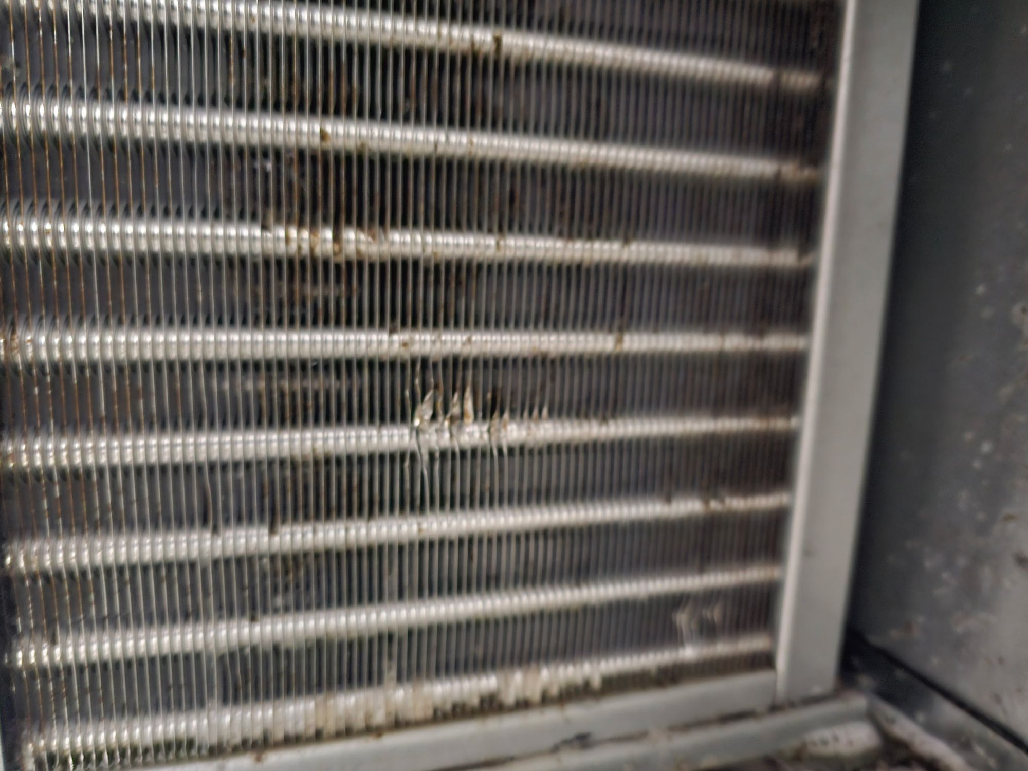 Close-up view of dirty and slightly damaged HVAC evaporator coils.