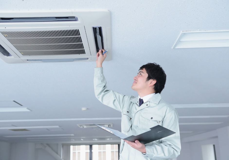Technician inspecting a ceiling AC unit.