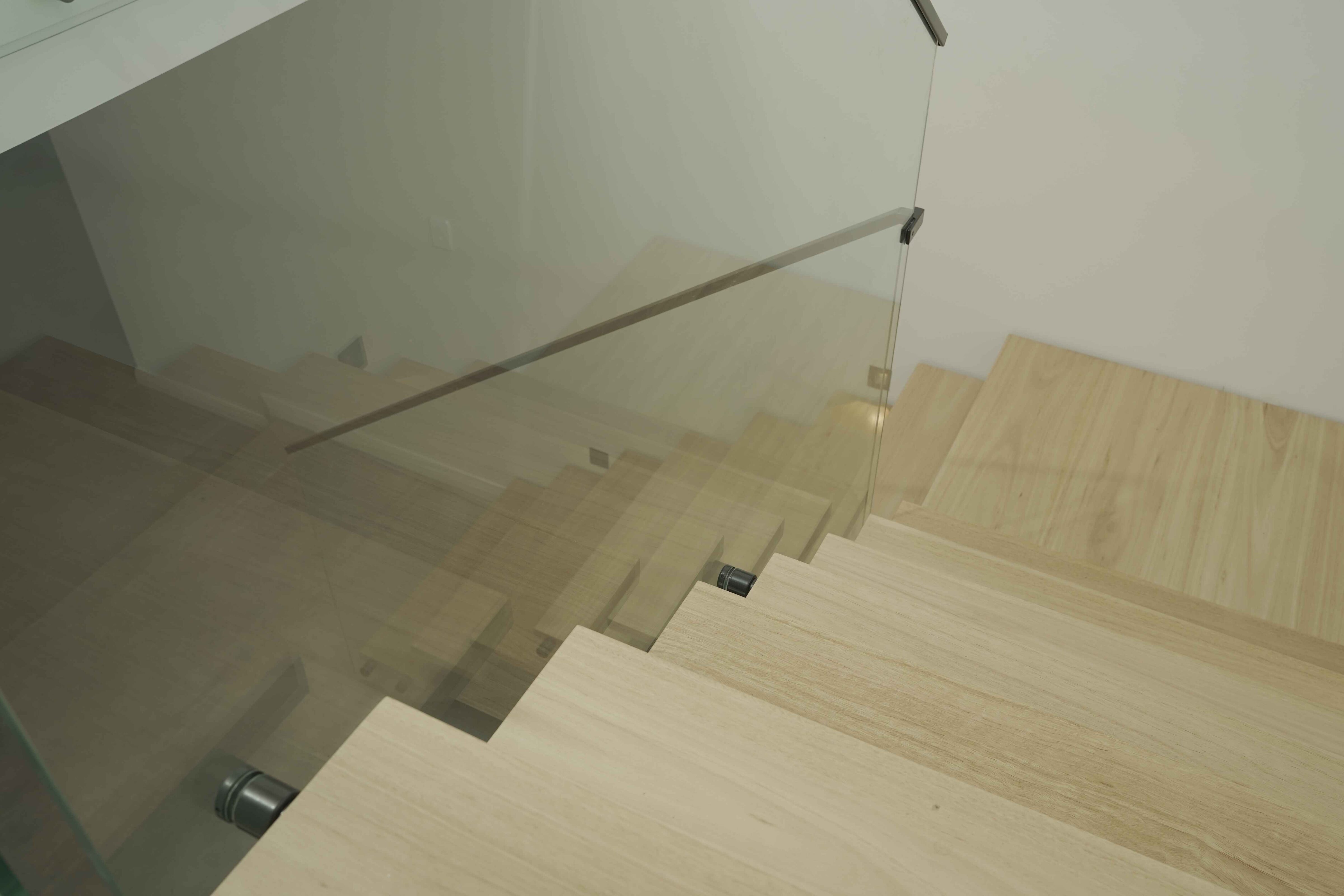Light timber staircase with frameless glass balustrade viewed from above.
