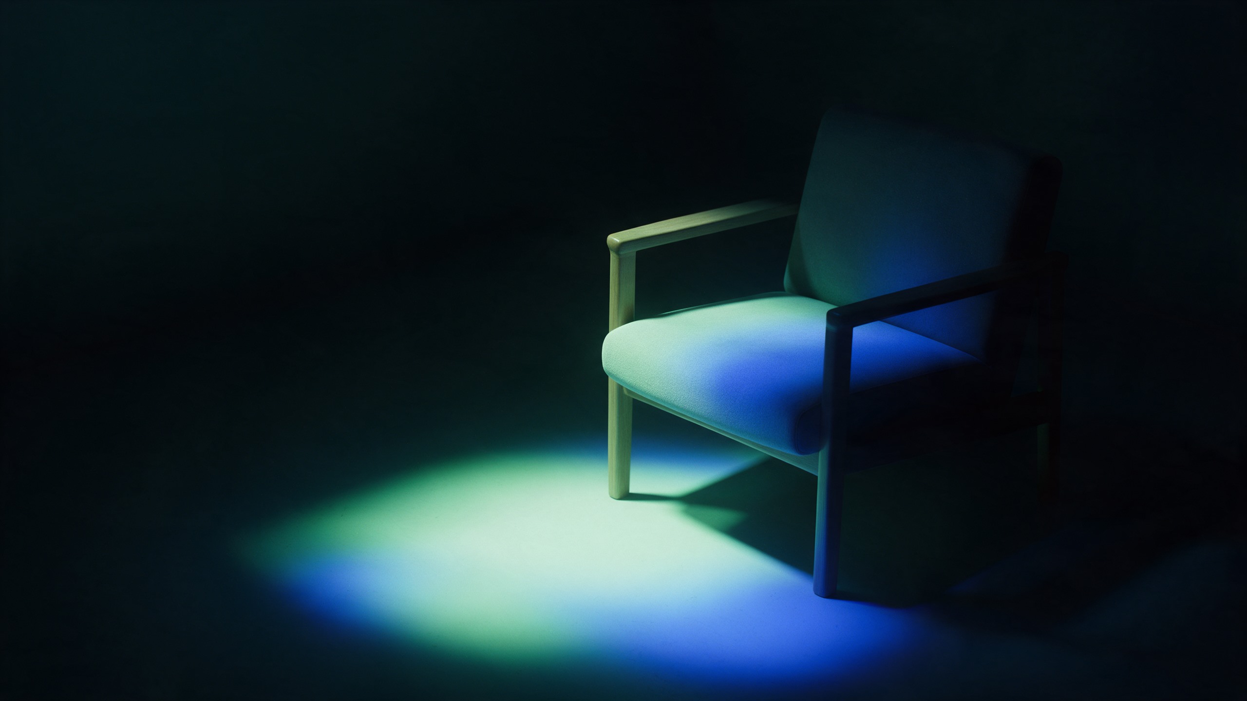 Fauteuil vide dans une pièce sombre, une lumière douce posée sur l'assise