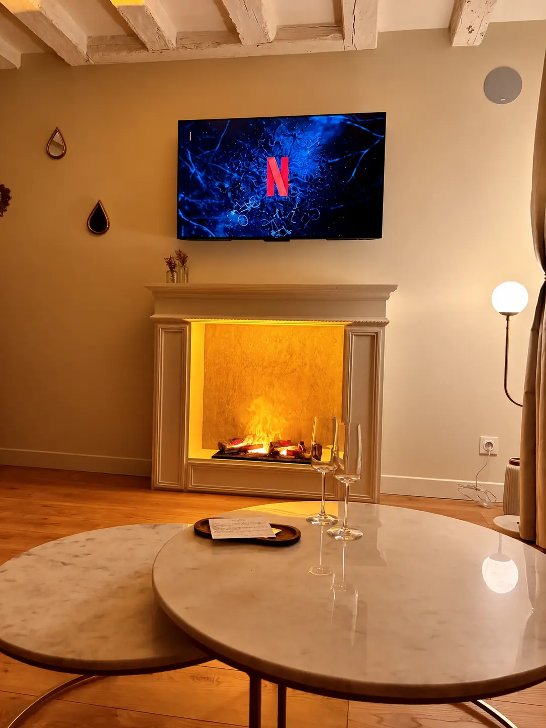 Salon chaleureux de la suite Lyra avec cheminée vapeur et télévision