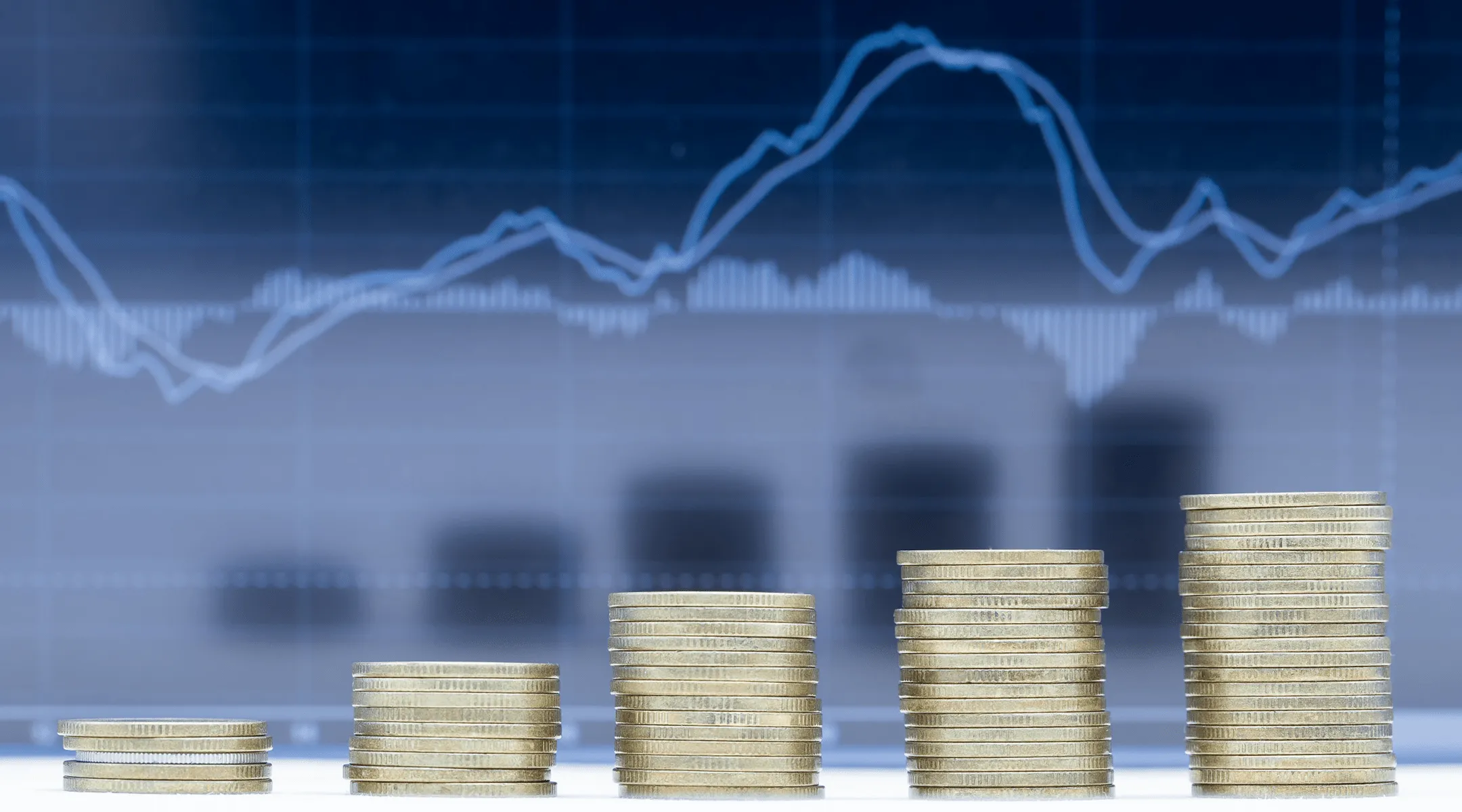 Повећавајуће стабилне гомиле новчића испред графикона са линијама тренда.