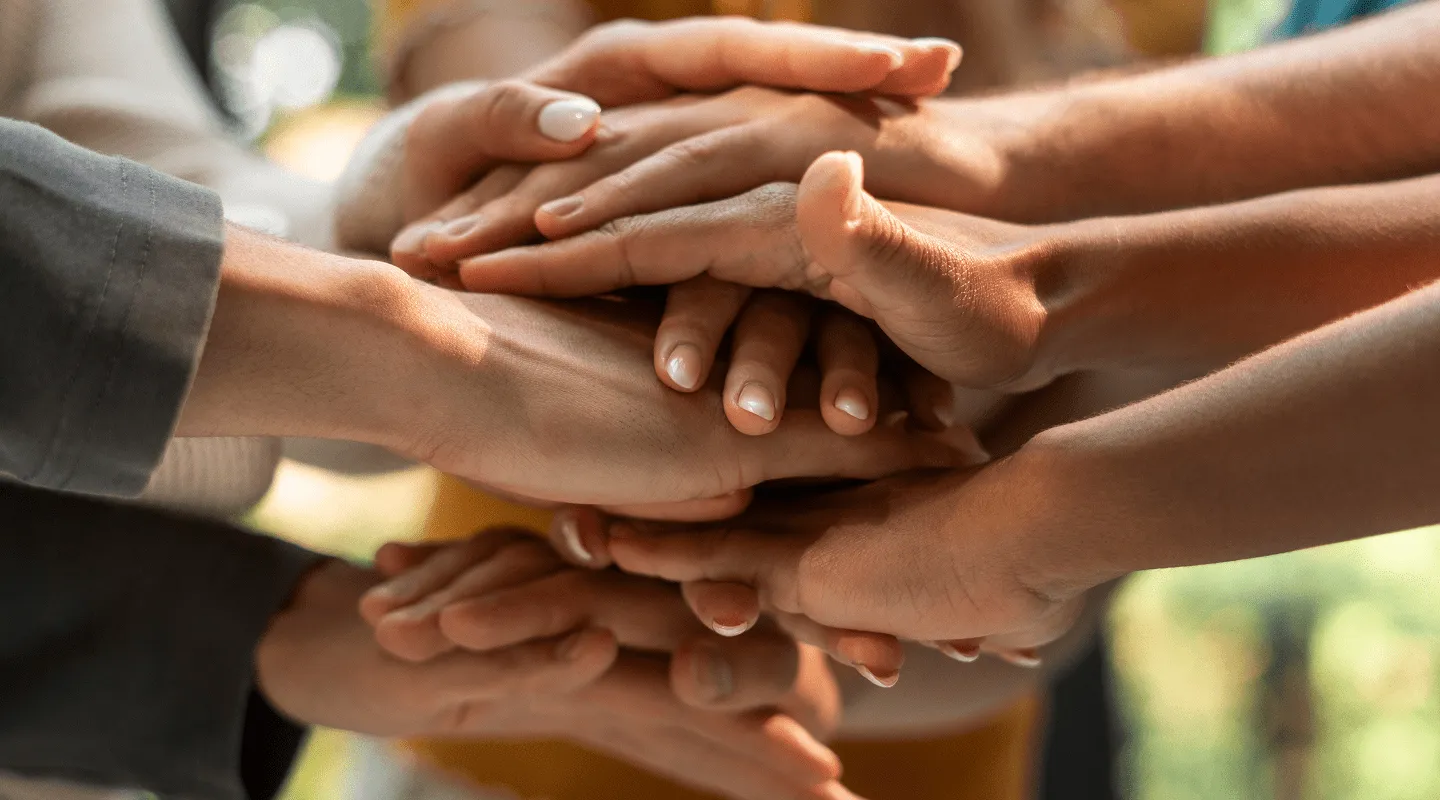 Ruke više ljudi složene zajedno u znak jedinstva i podrške.