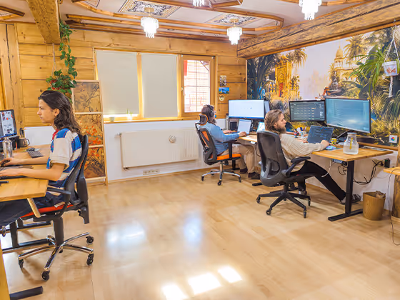 Mitarbeiter:innen von Leto AI arbeiten im offenen Büro mit Holzdekor und Dschungel-Wandmotiv an mehreren Monitoren