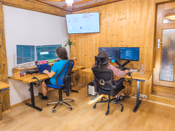 Mitarbeiter:innen von Leto AI arbeiten im offenen Büro mit Holzdekor und Dschungel-Wandmotiv an mehreren Monitoren