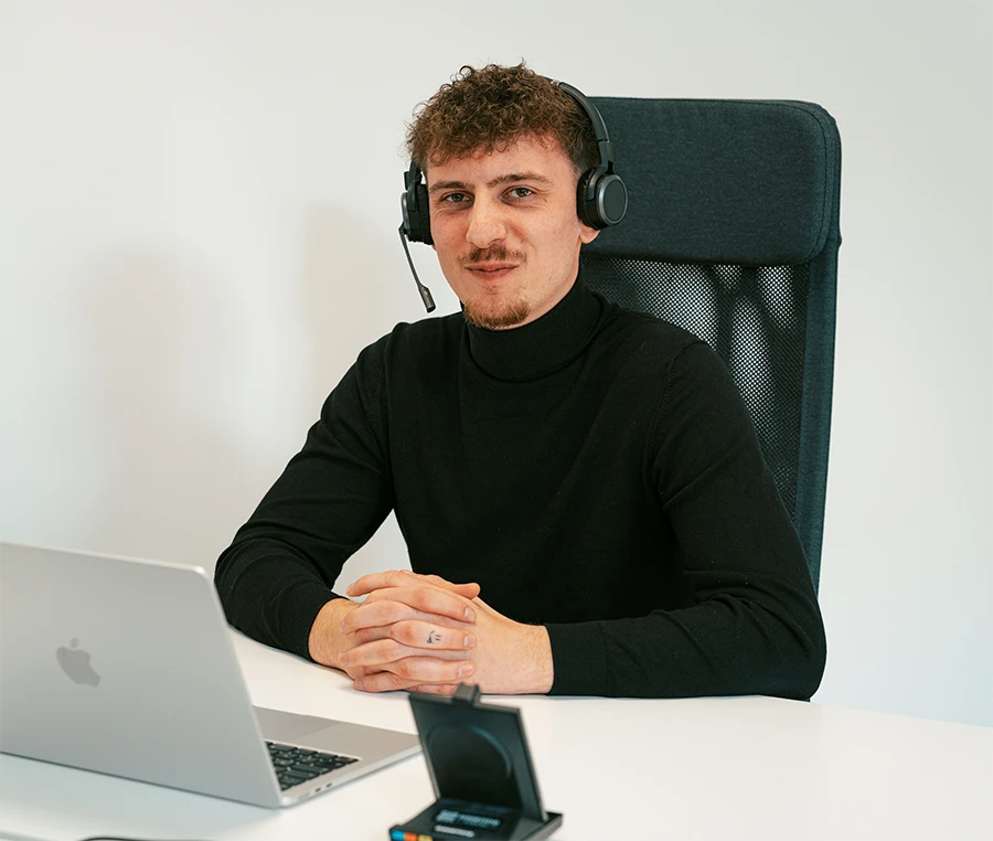assentio Werkstudent/Praktikant im Bereich Sales Management sitzt mit Headset am Schreibtisch.