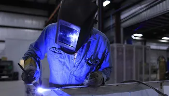 Welder working with bright blue light in industrial workshop