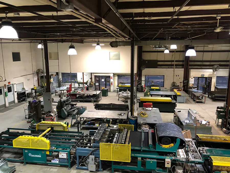 Industrial workshop with machinery, workbenches, and yellow safety guards