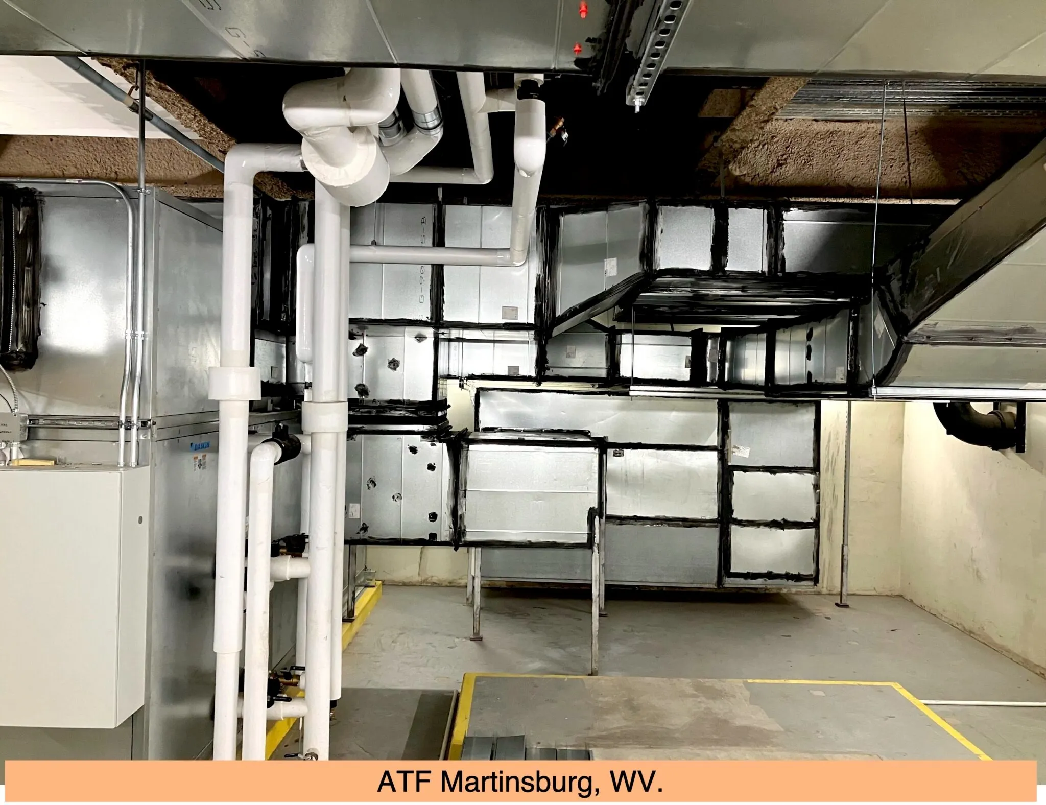 Industrial mechanical room with white pipes, ductwork, and equipment