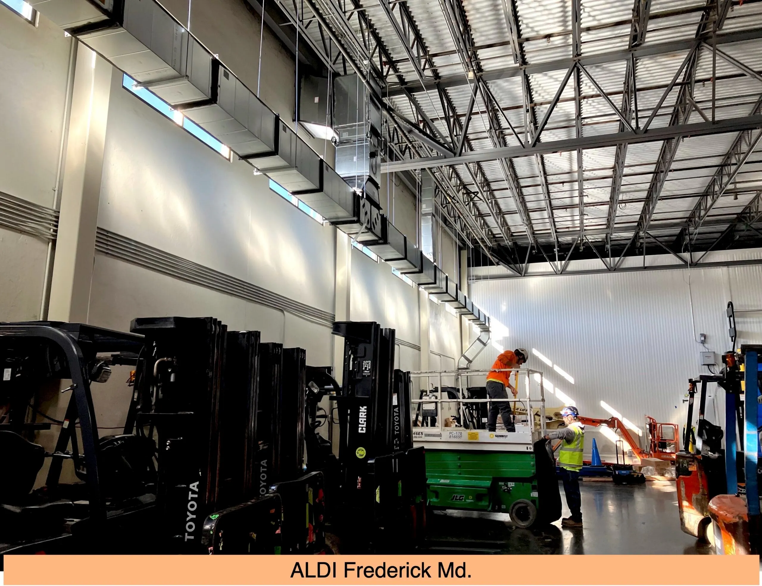 Warehouse interior with forklifts and workers on scissor lift
