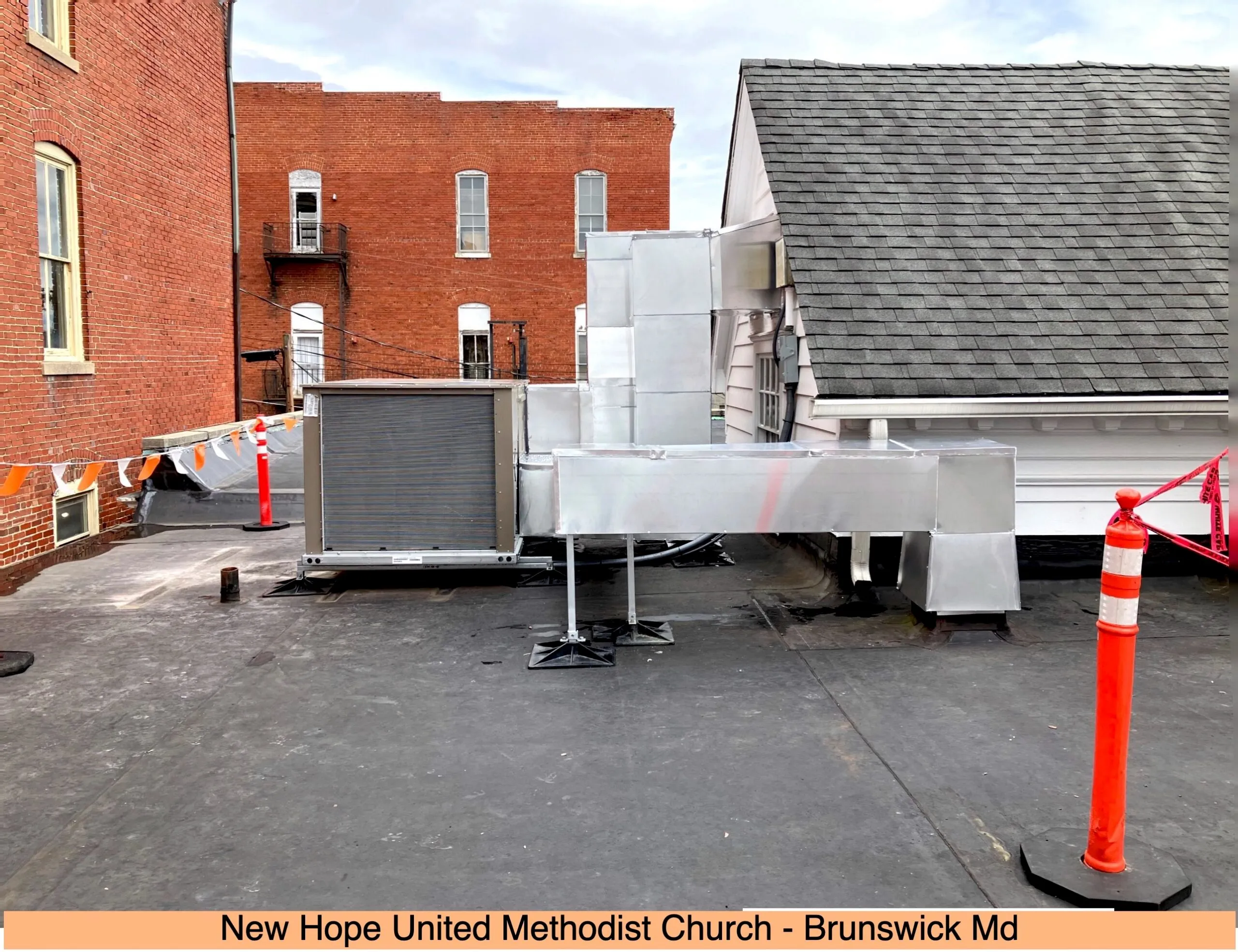 HVAC equipment on roof with red safety markers and brick buildings