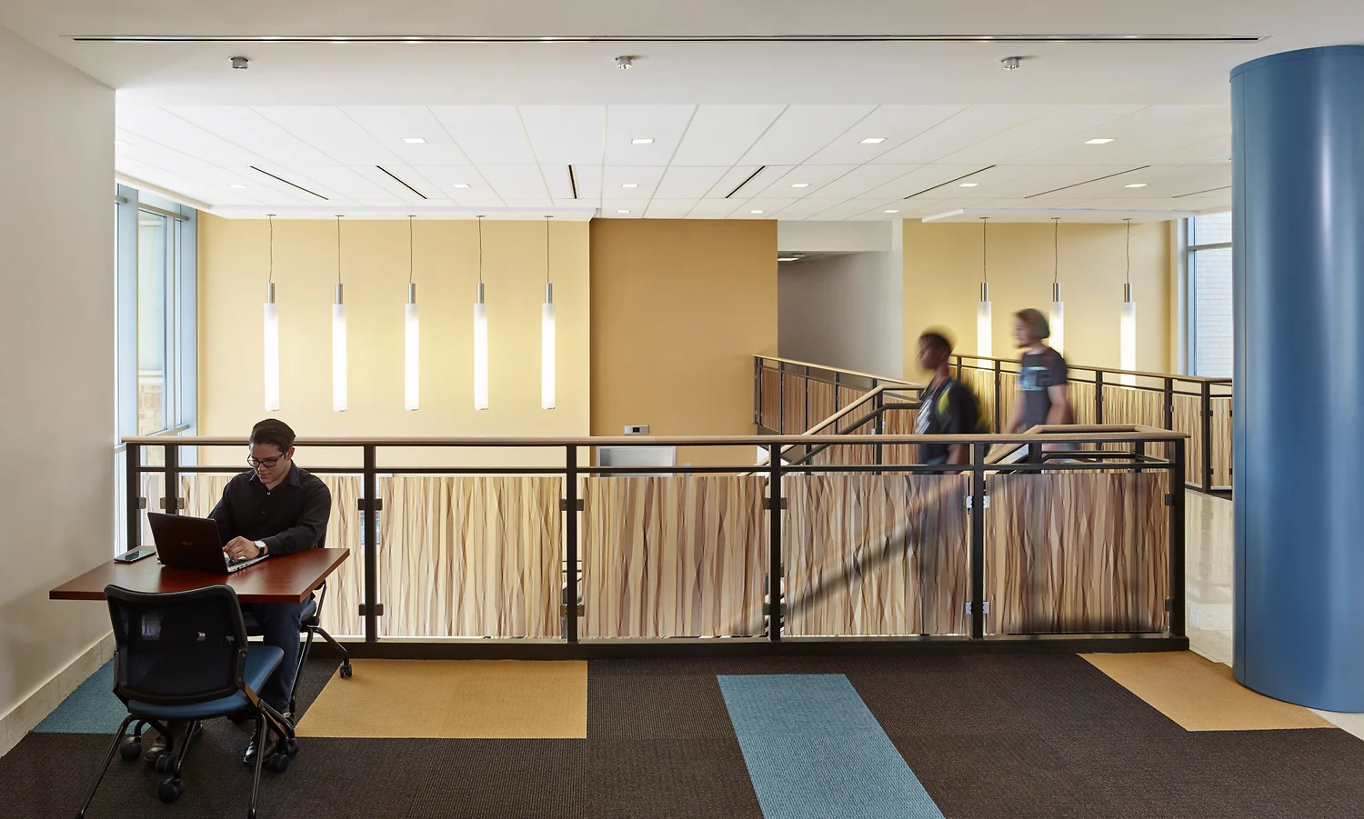 A brightly lit office with a person working on a laptop.