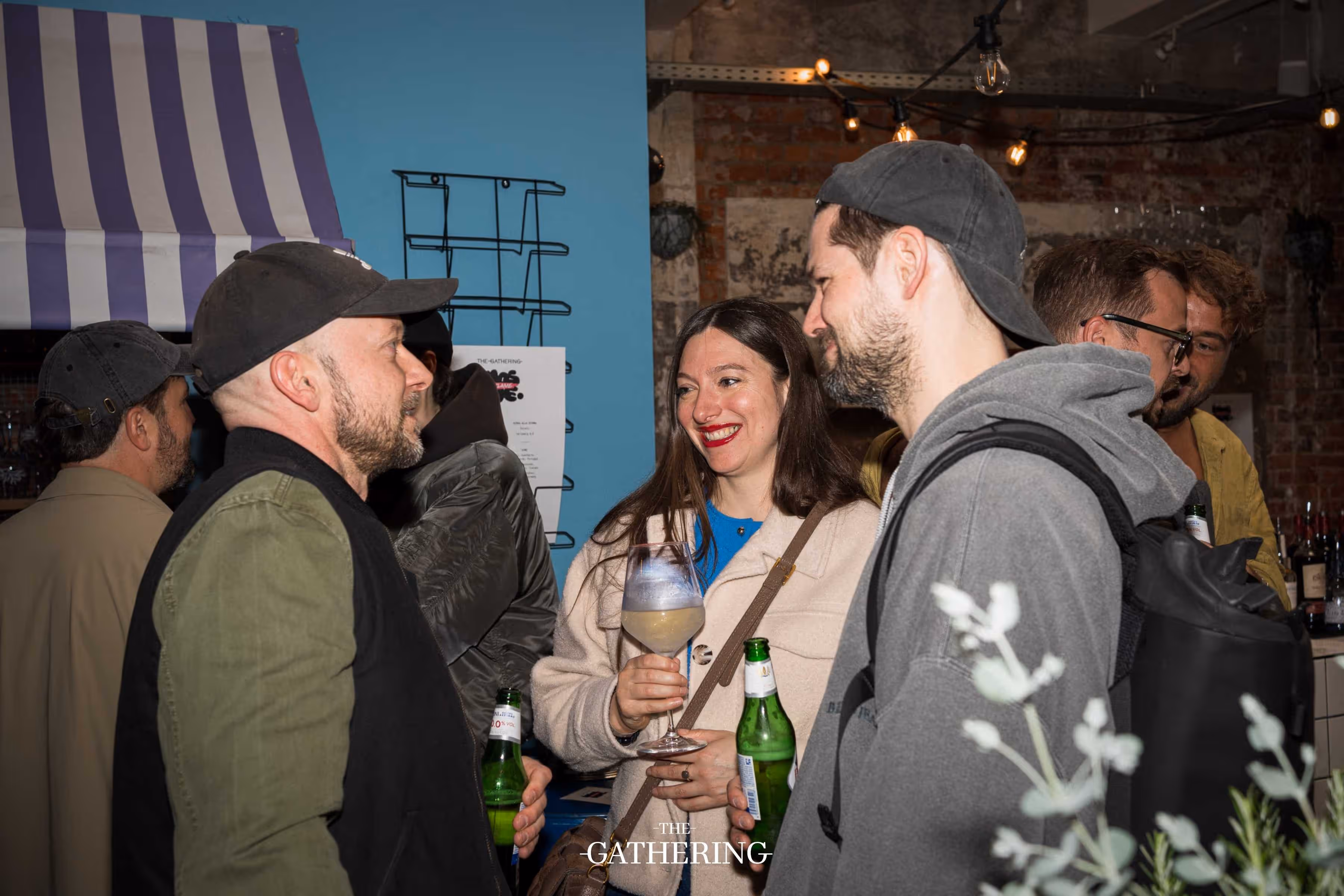 Crowd mingling around tables with drinks at The Gathering hosted by Maison ACME