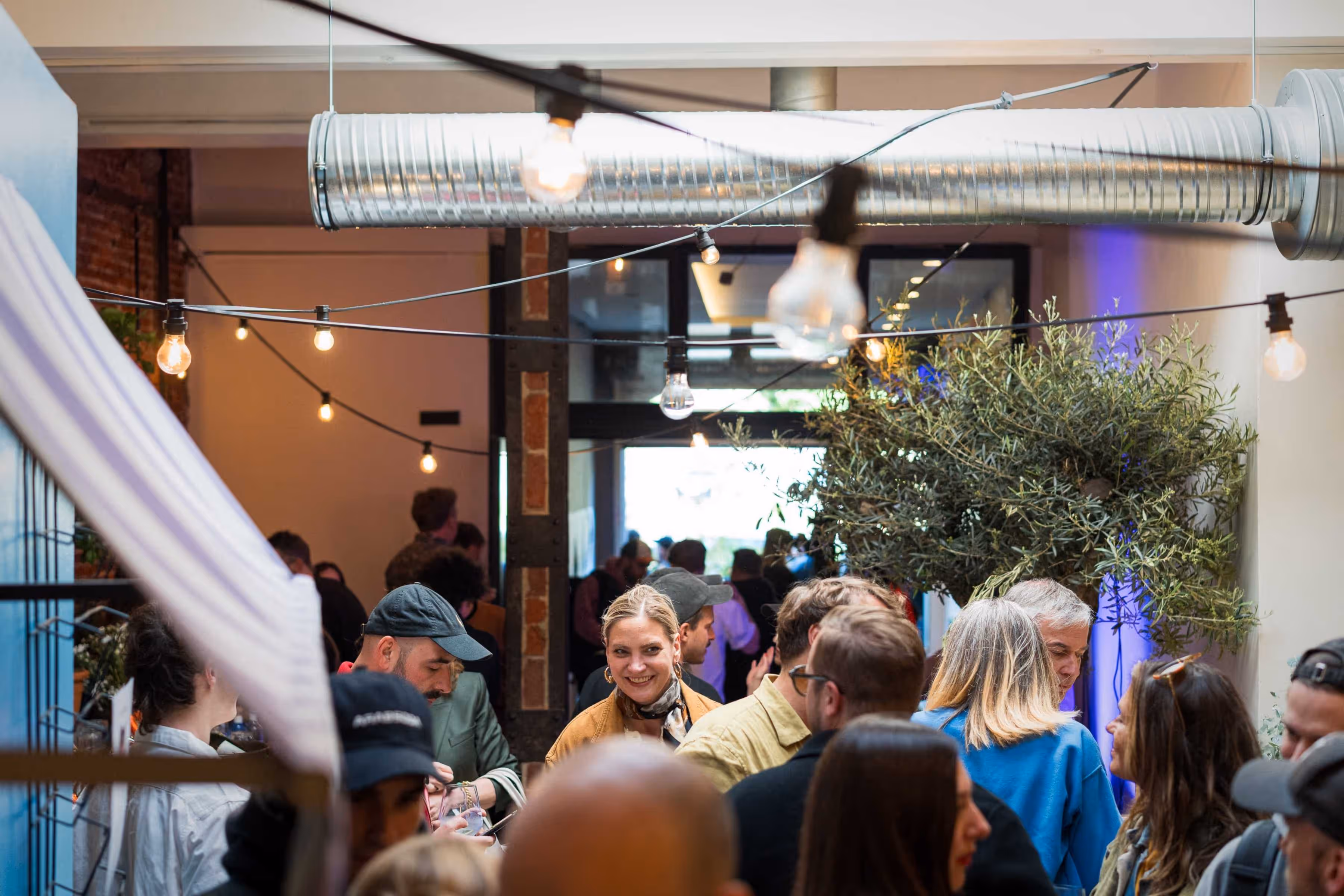 Crowd mingling around tables with drinks at The Gathering hosted by Maison ACME