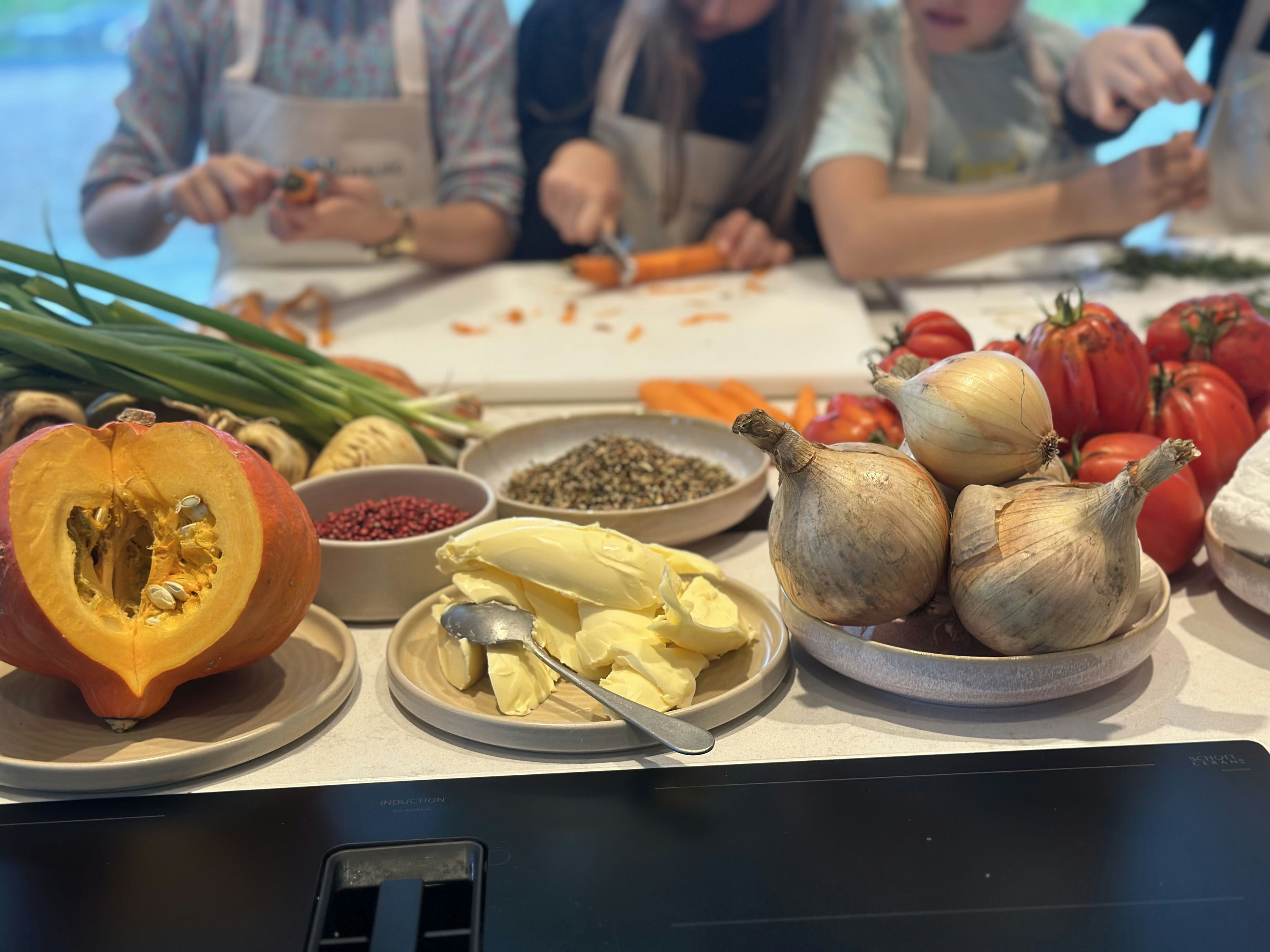 Kürbis, Butter, Zwiebeln im Vordergrund, Kinder schnibbeln Karotten im Hintergrund