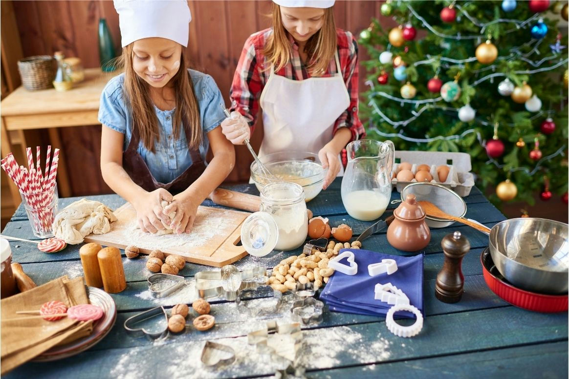 Kinder backen, im Hintergrund ein Weihnachtsbaum