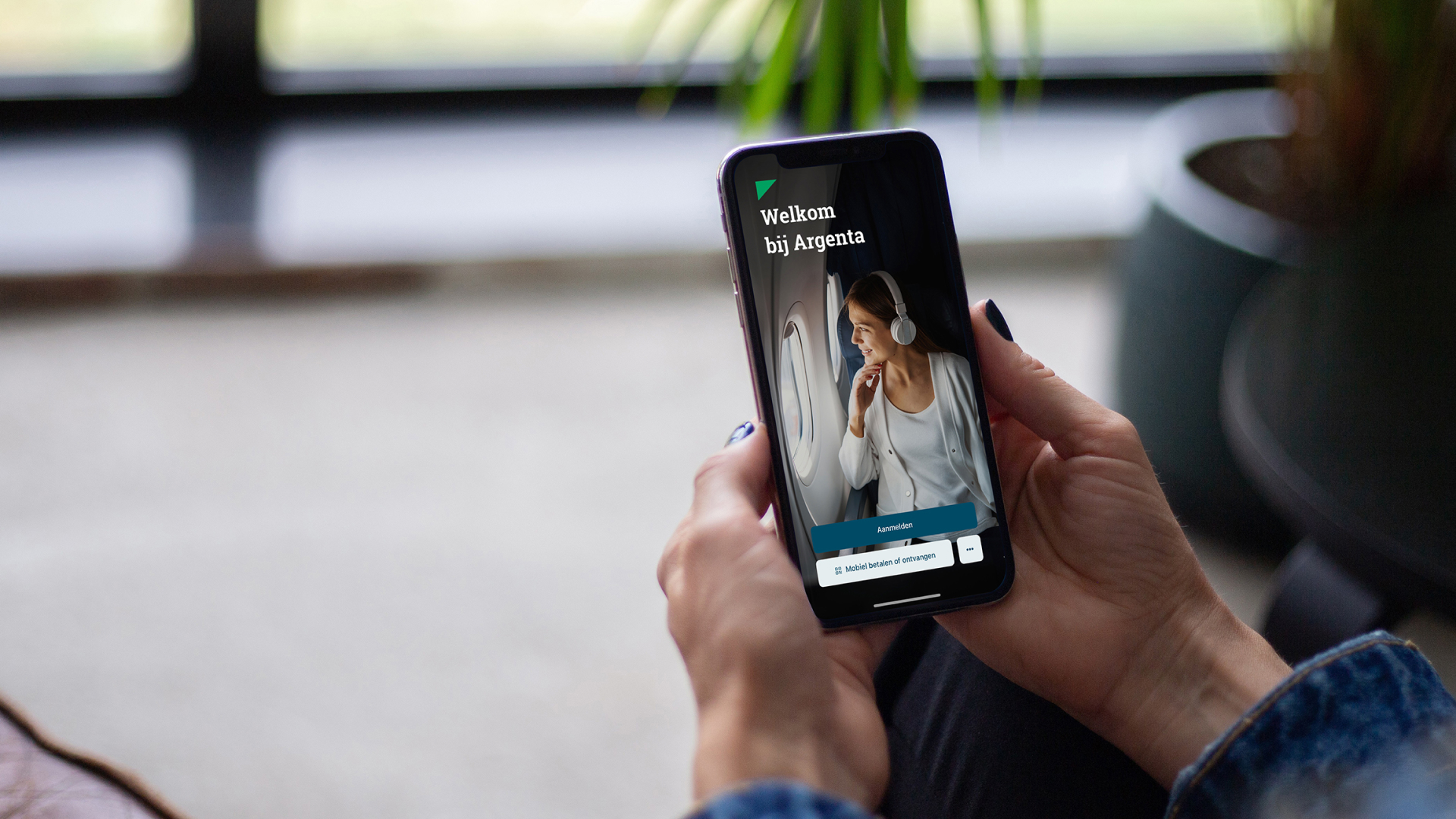 User is holding a mobile phone in their hand and on the screen is the mobile application of Argenta