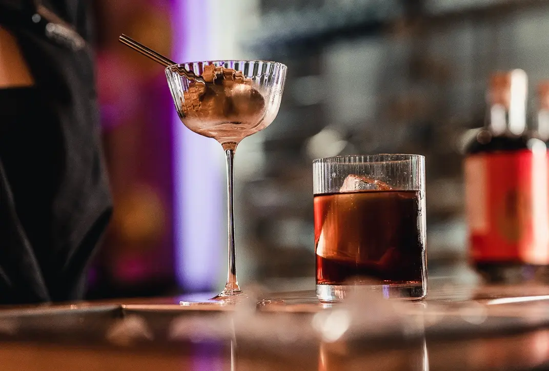 A delicious black cocktail accompanied by an italian gelato in a beautiful crystal coupe.