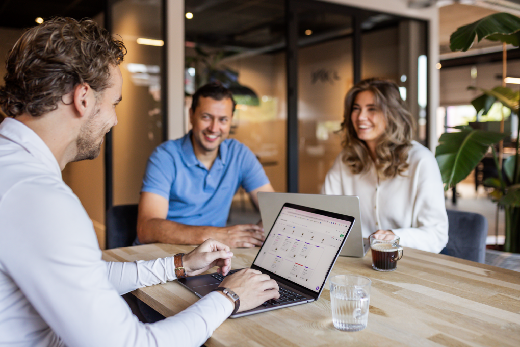 Twee mensen in gesprek terwijl vPlan projectmanagementsoftware op een laptop wordt getoond.