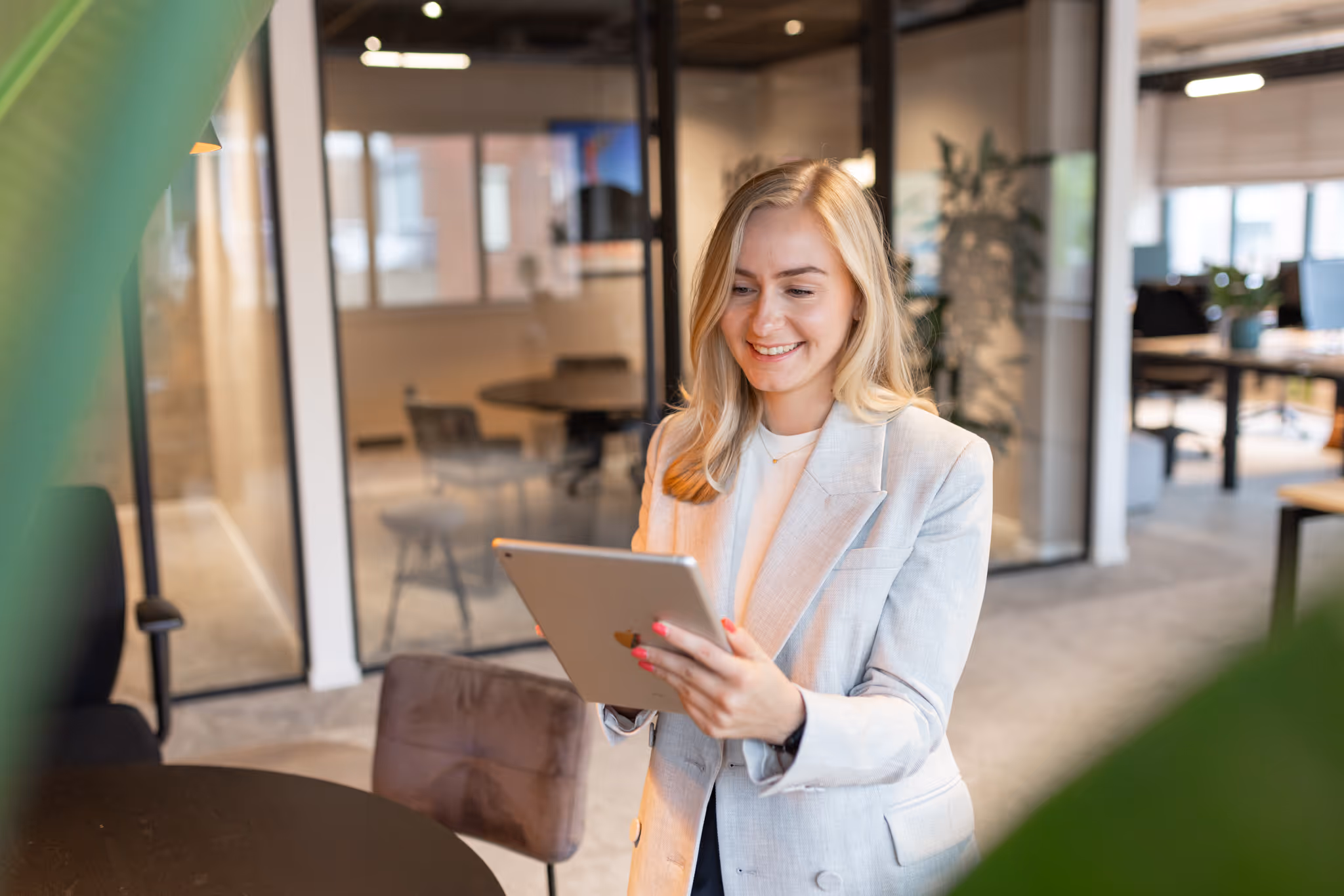 Woman using a tablet in a modern office to manage her schedule with vPlan, in an inspiring workspace.