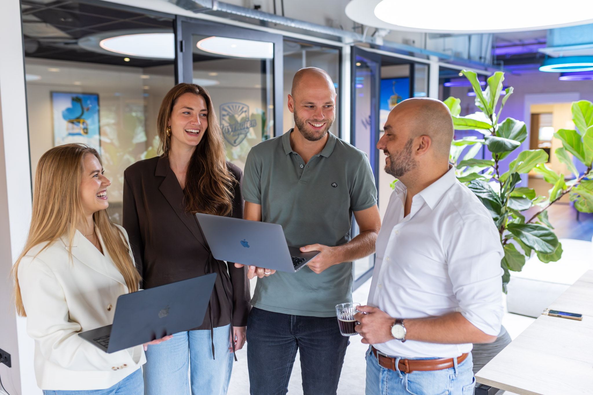 Four colleagues with laptops talking through a solution together