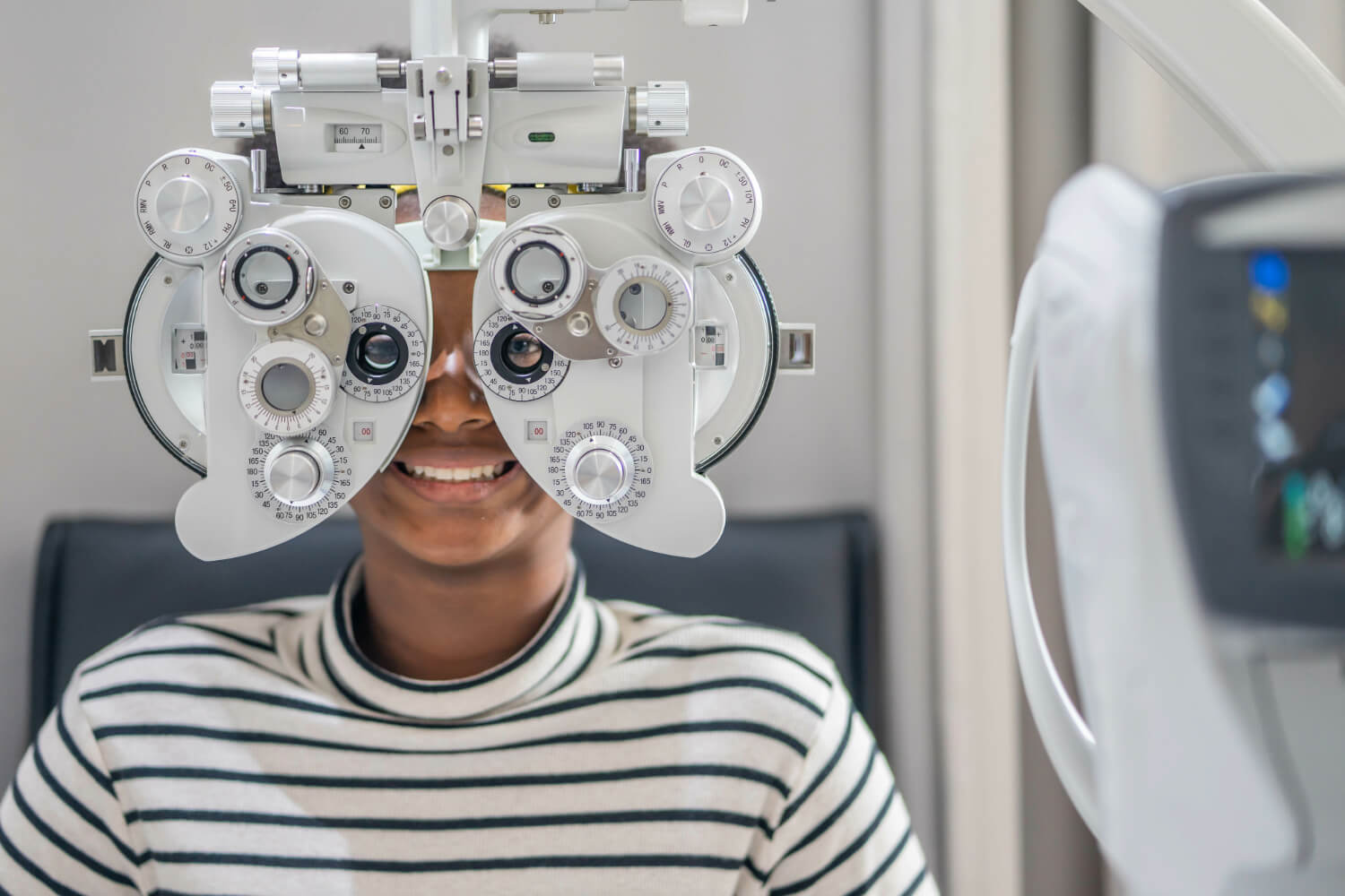 Patient smiling during eye exam with phoropter