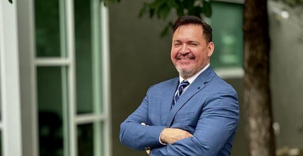 Dr. Trinidad in suit with arms crossed outdoors