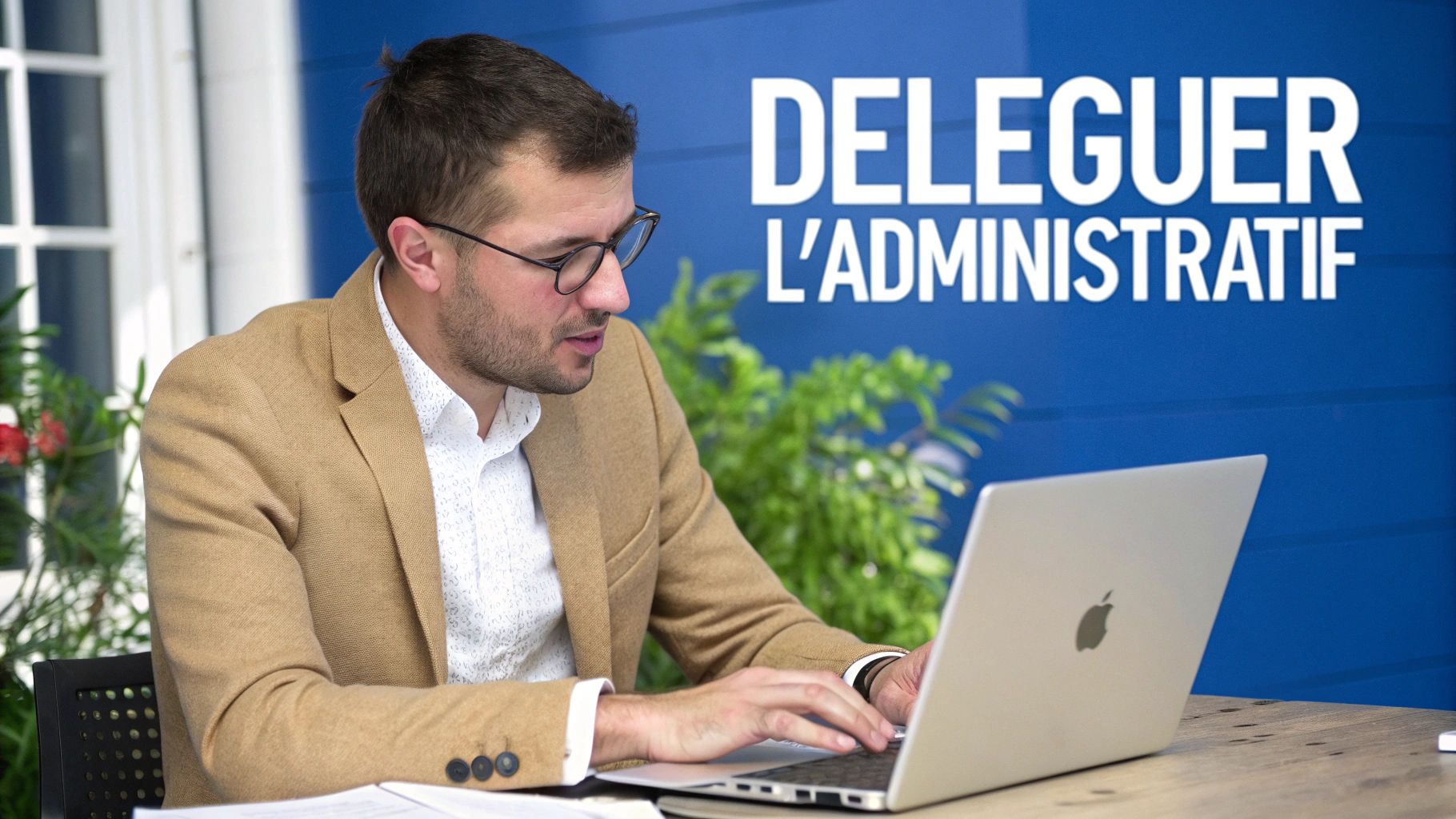 Homme en blazer et lunettes, travaillant sur un ordinateur portable devant un mur bleu avec le texte "DELEGUER L'ADMINISTRATIF".