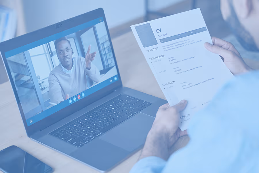 Person holding a CV while video interviewing with a man on a laptop screen.