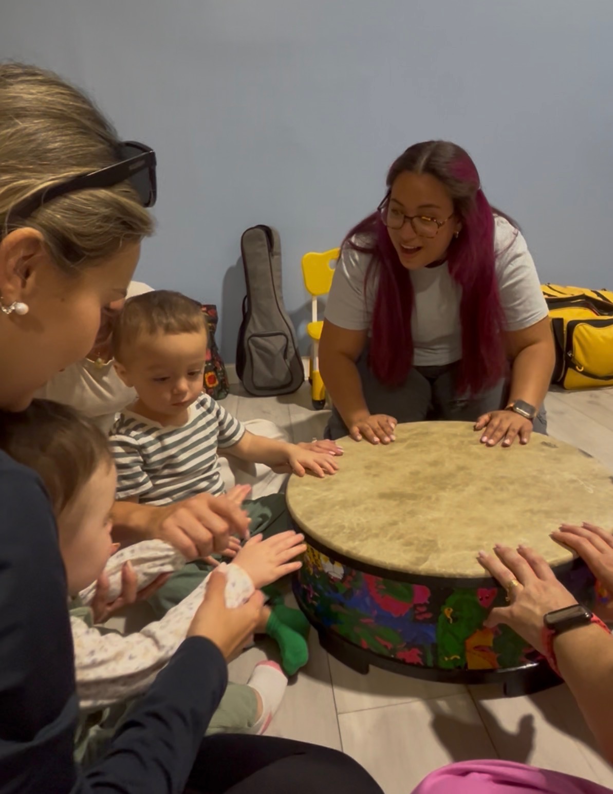 Caregivers and children drumming together with Gabriela