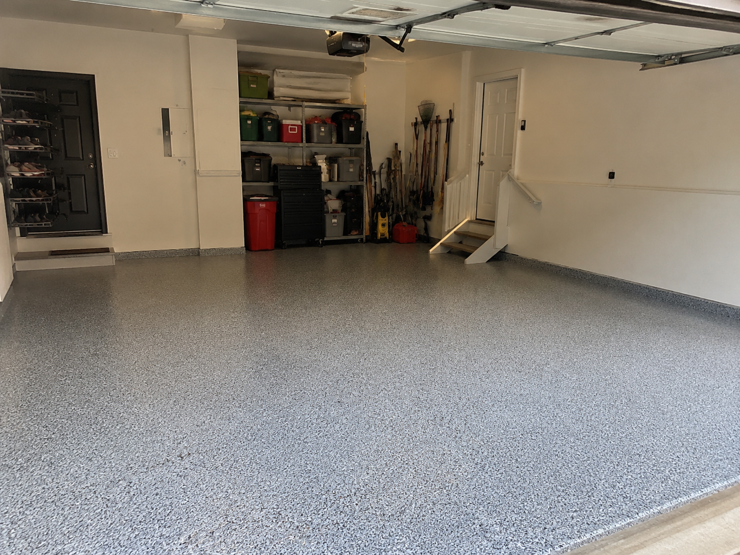 Freshly coated gray epoxy garage floor with decorative flakes in a clean two-car garage.