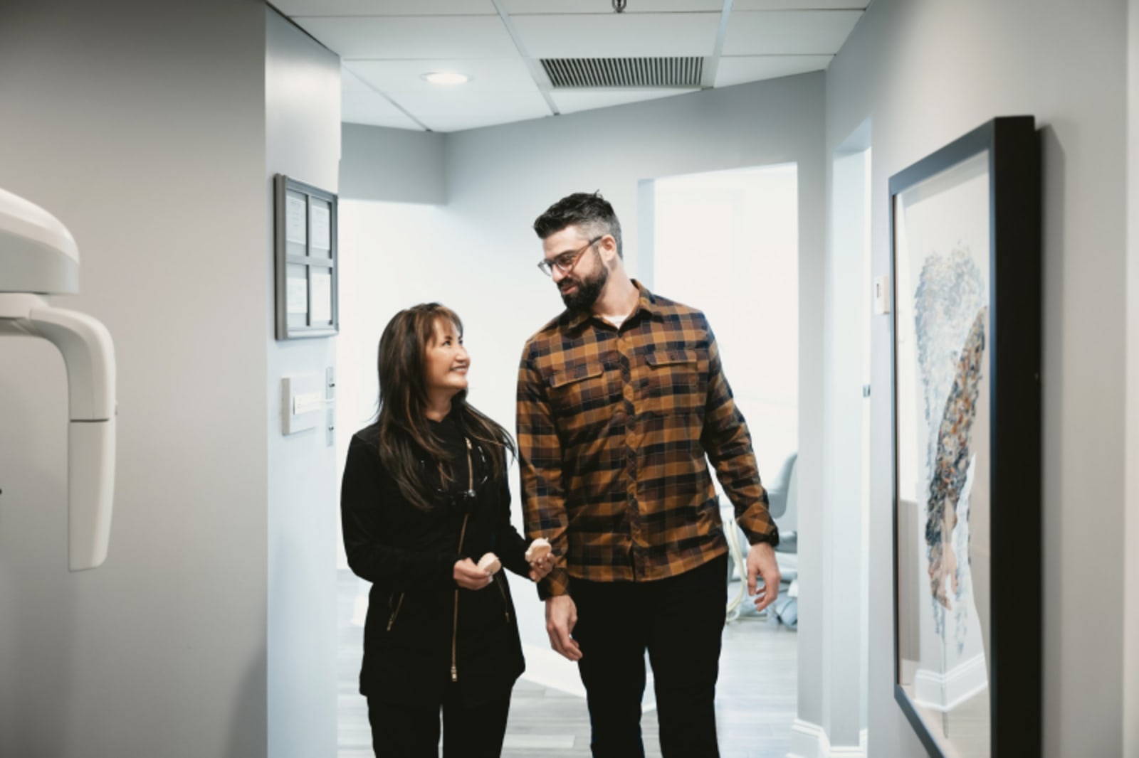 Male and female dental professionals walking together down modern clinic hallway discussing treatment