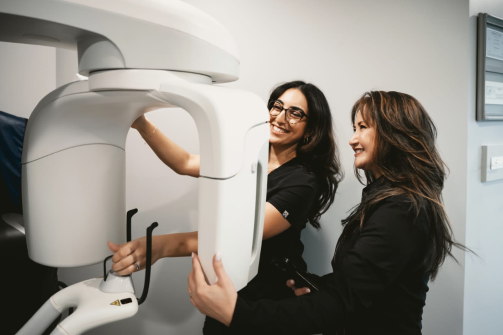 Two dental professionals consulting over digital imaging equipment in clinical setting