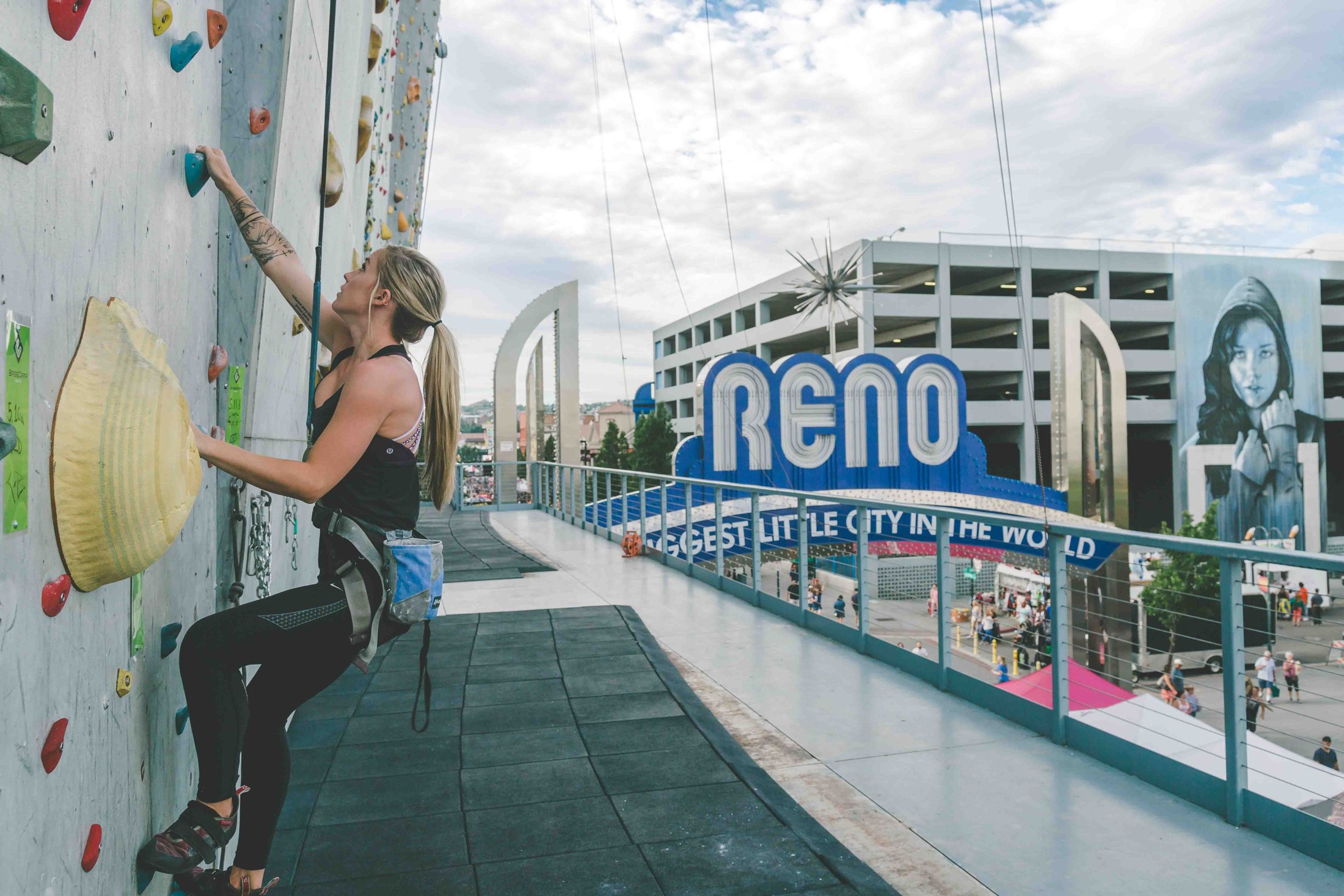 Climber on BaseCamp's outdoor wall with the Reno sign nearby