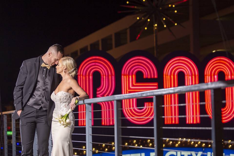 Couple celebrating beside the Reno Arch outside Whitney Peak Hotel