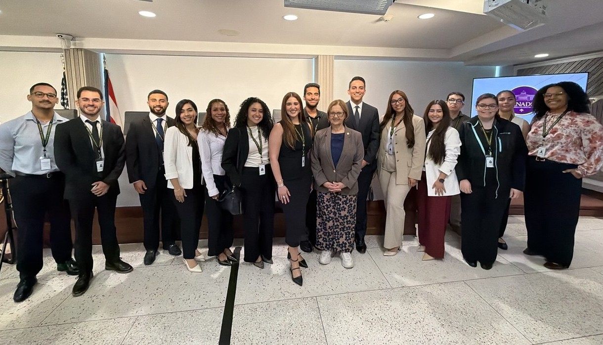 Grupo de cinco jóvenes profesionales, de pie uno al lado del otro, sonriendo y abrazados en un entorno moderno. La imagen transmite diversidad, compañerismo y entusiasmo, ideal para representar un programa de internado inclusivo y colaborativo.