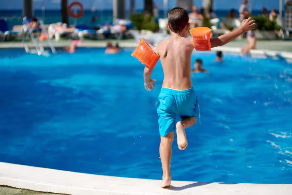 Child on a business trip jumping into pool