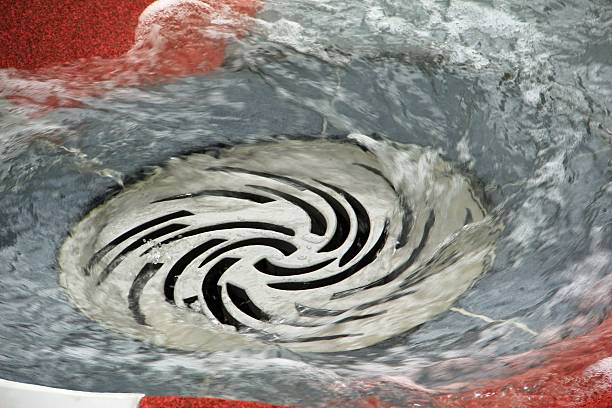Water swirling down a drain with a spiral design.
