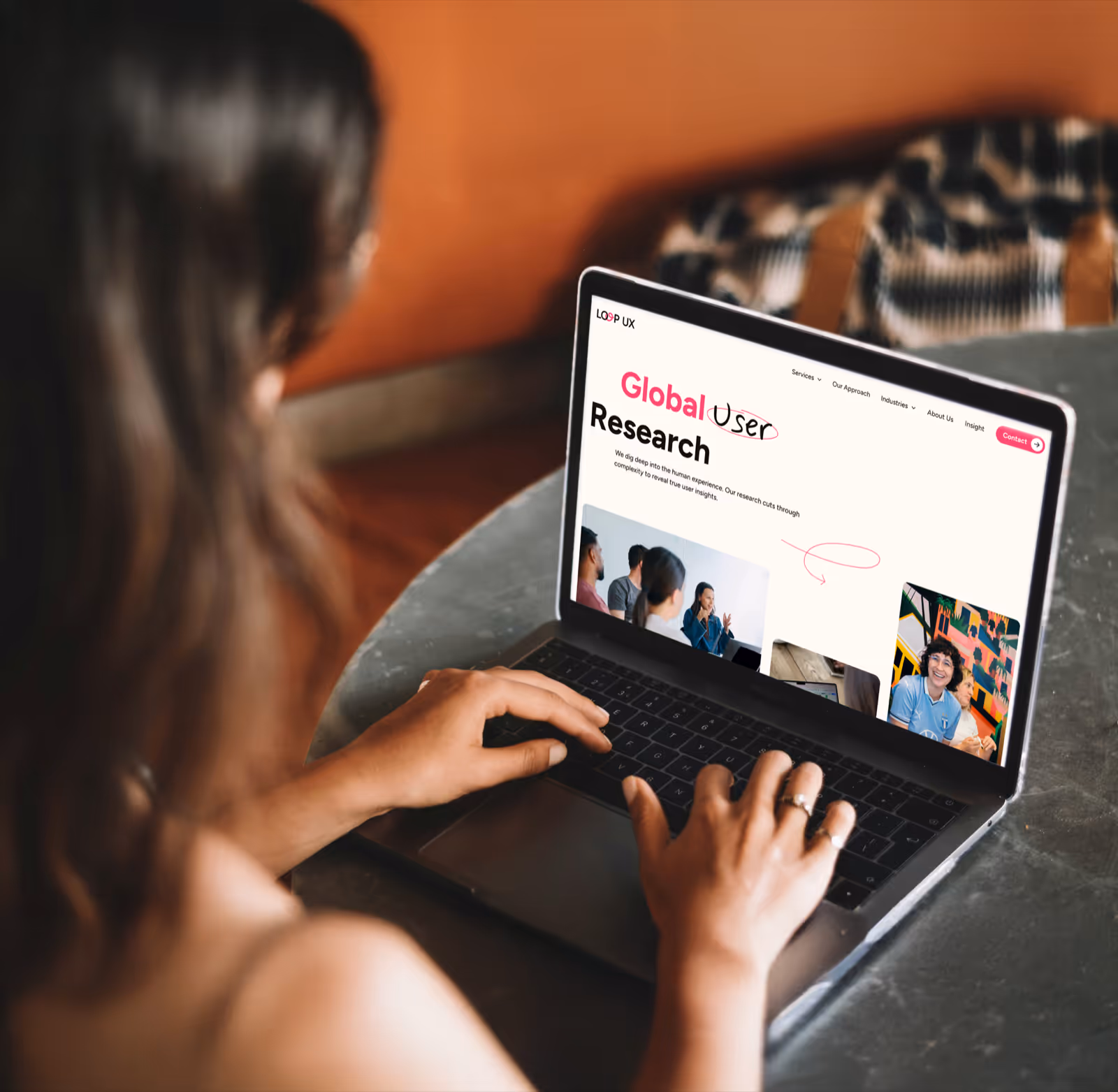 Person typing on a laptop showing a webpage titled 'Global User Research' with images of people and navigation menu.
