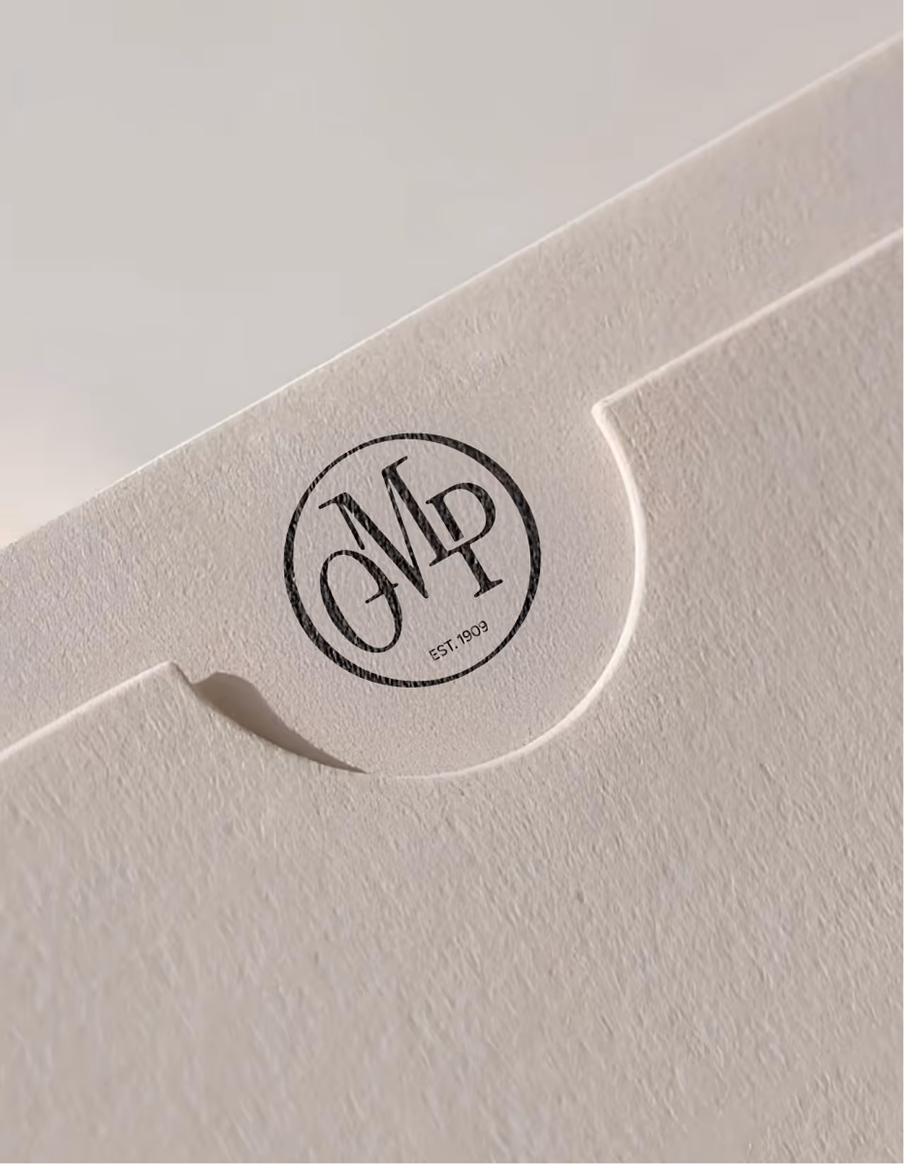 Textured beige folder with a round black logo containing the OMP logo