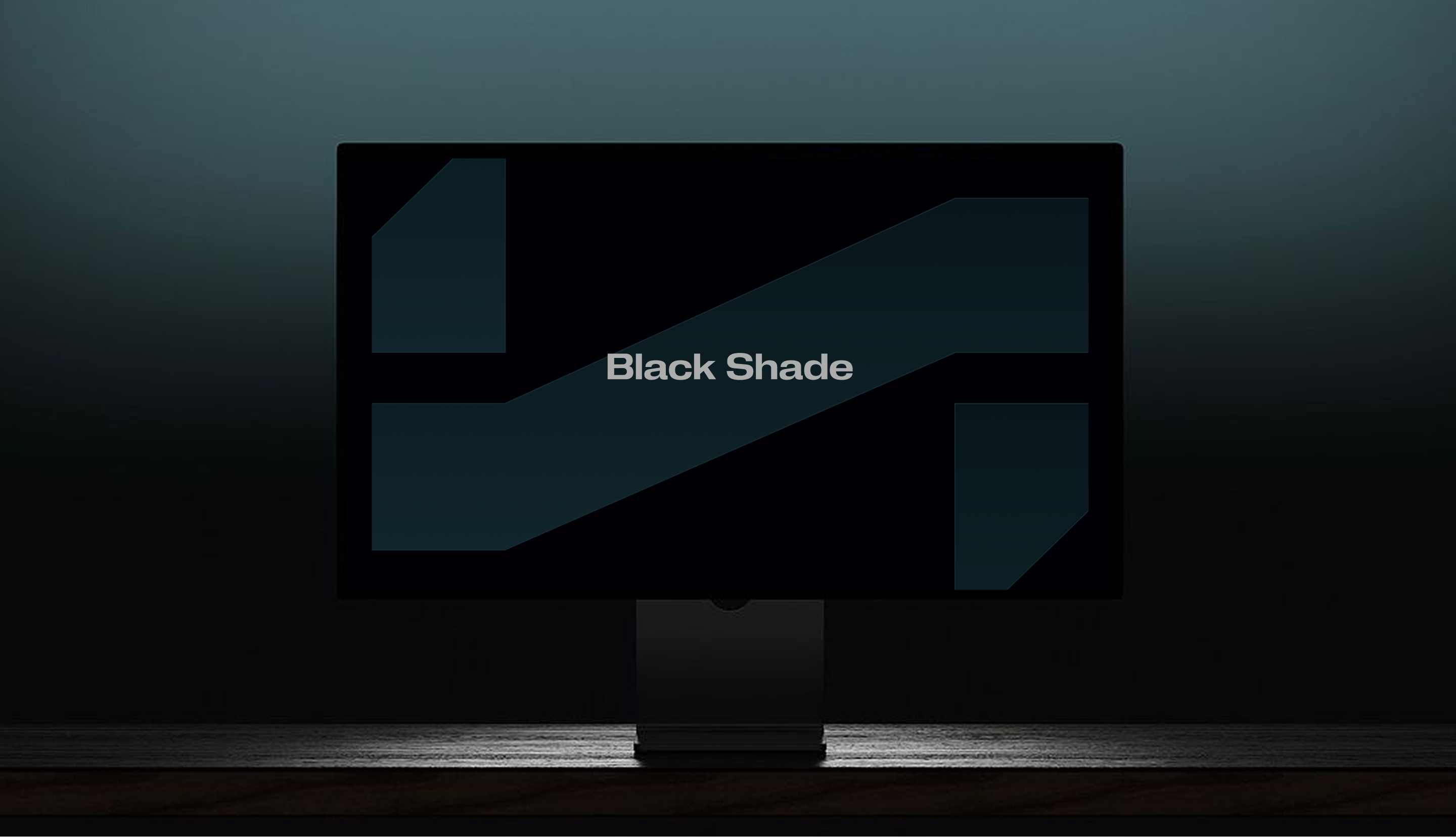 Computer monitor on a dark wooden desk displaying the words Black Shade on screen.