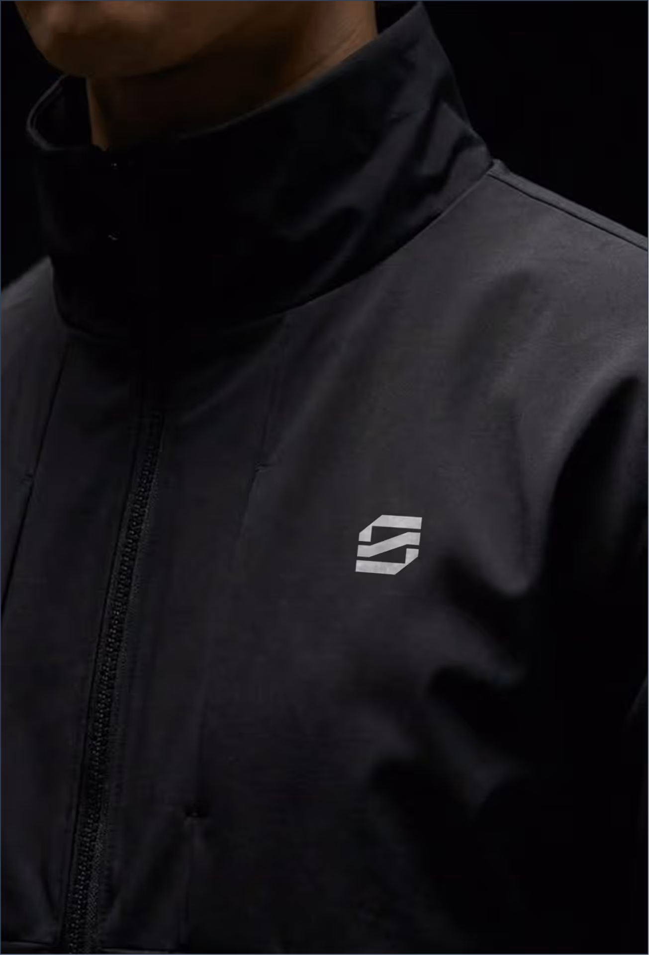 Close-up of a person wearing a black jacket with a small white Black Shade logo on the chest.