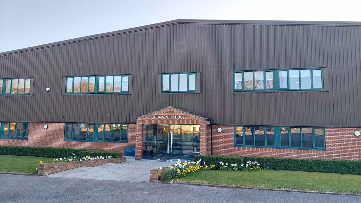 A large brown building with green windows and a sign reading "CoModity House" at the entrance.