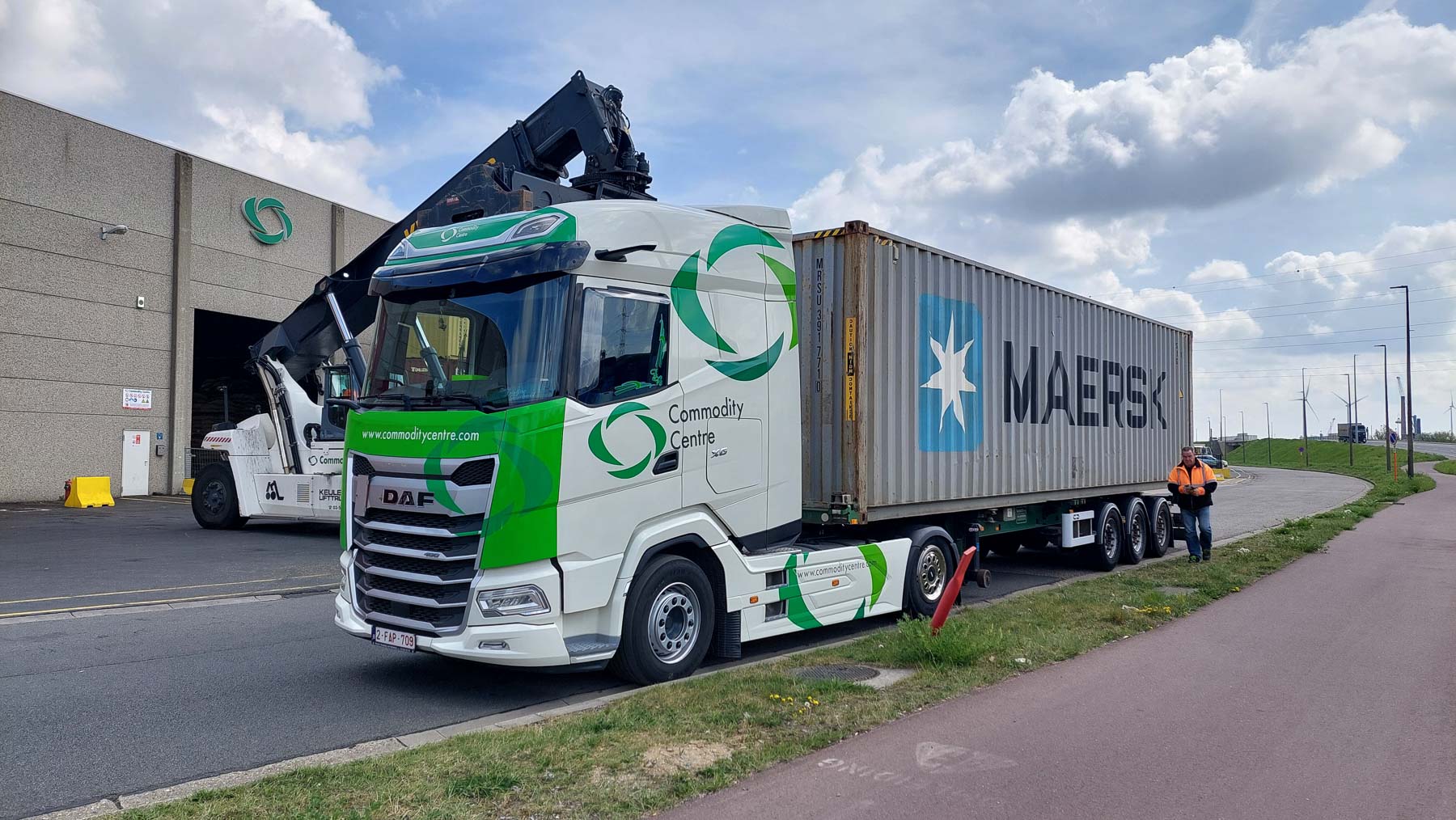 A commodity centre delivery truck pulled up next to a large industrial building