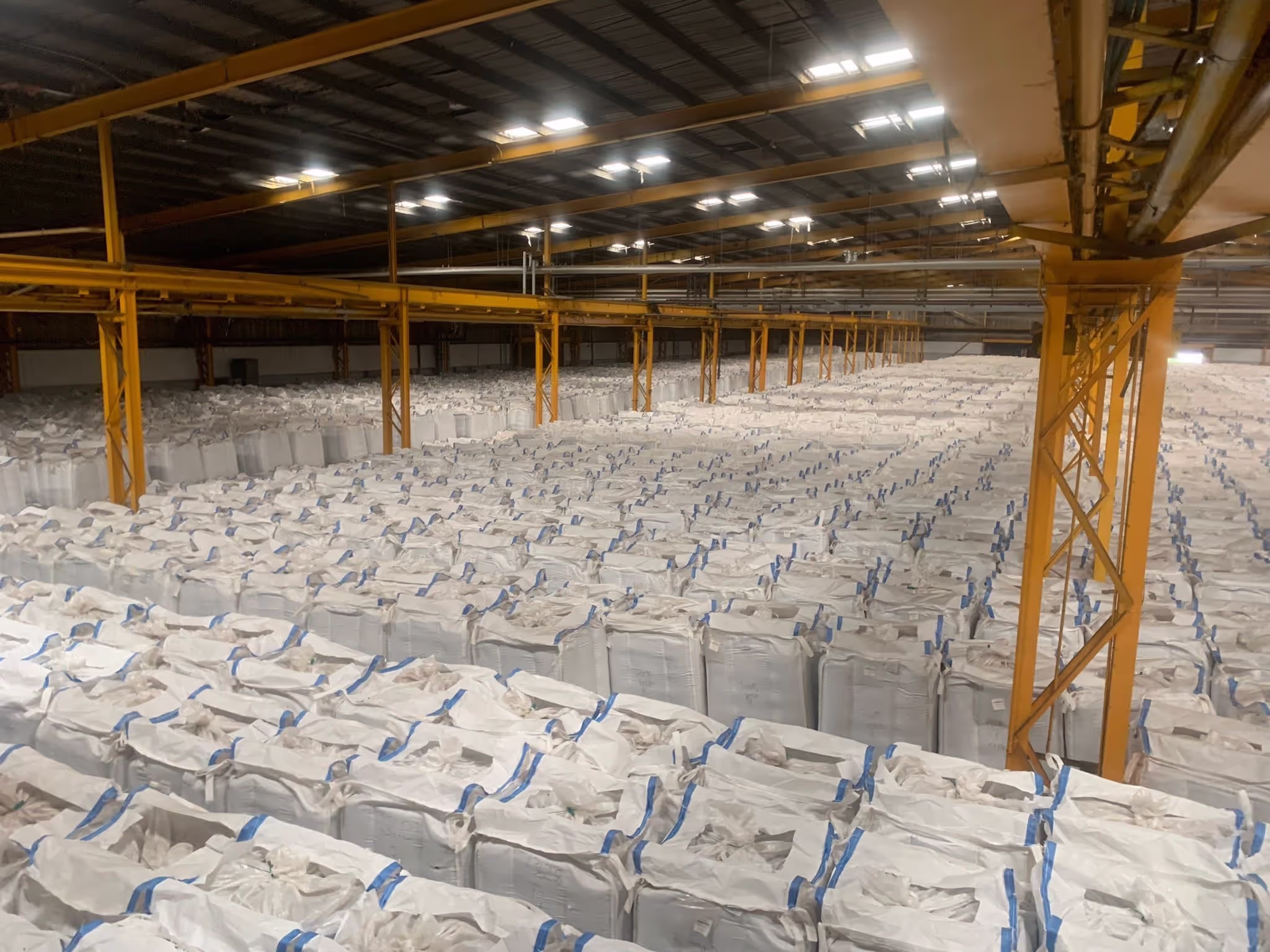 The interior of a large industrial building with hundreds of white bags next to each other