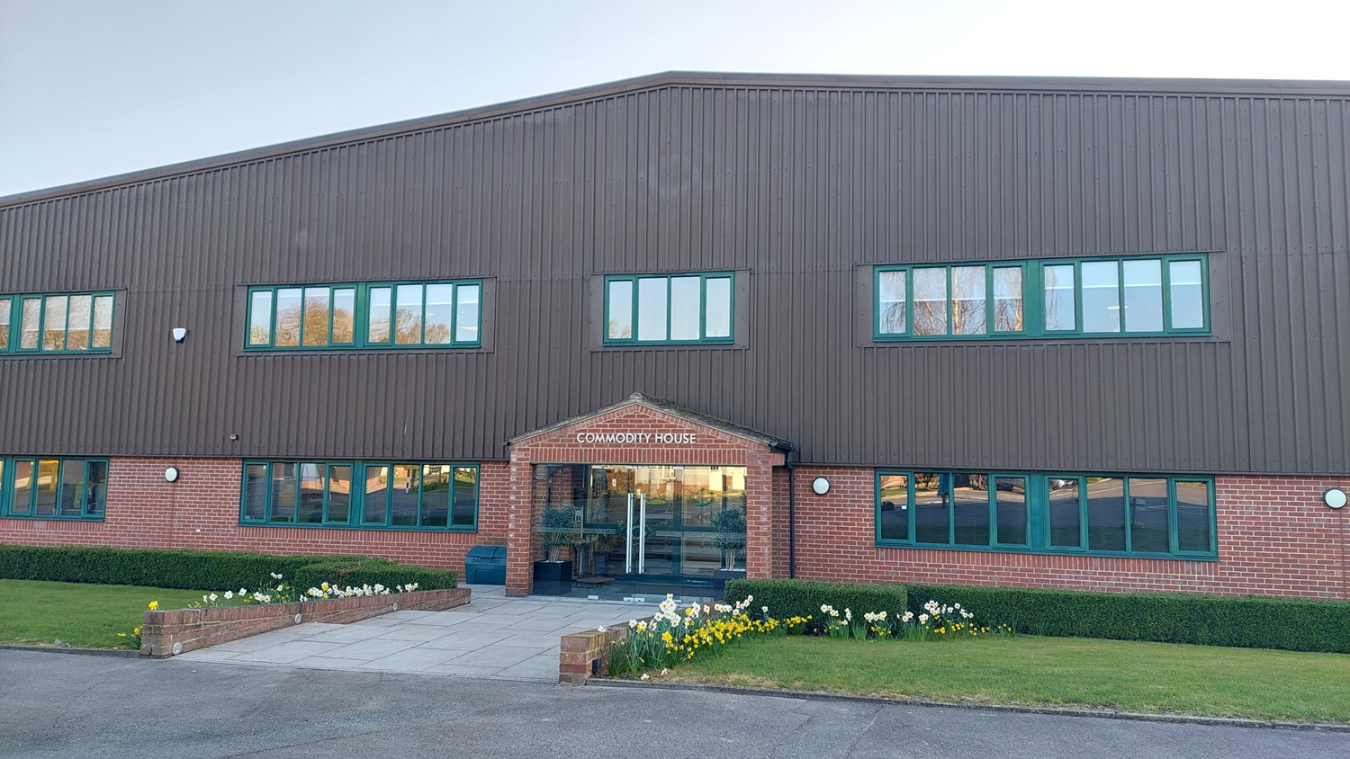 Large industrial building labeled "Commodity Centre" with flags and a surrounding fence under a blue sky.