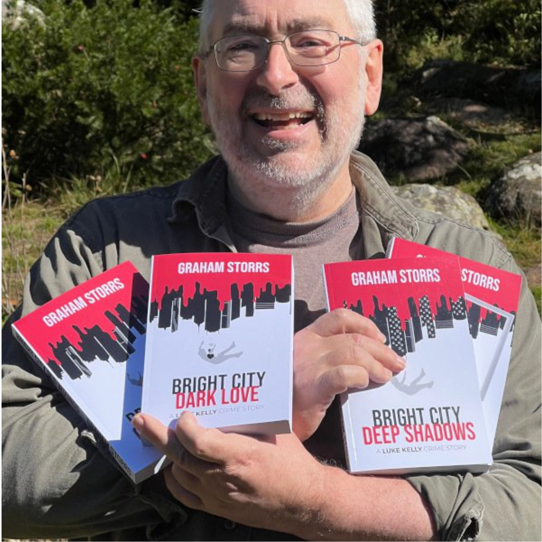 Author Graham Storrs holding all four of his crime novels and smiling.
