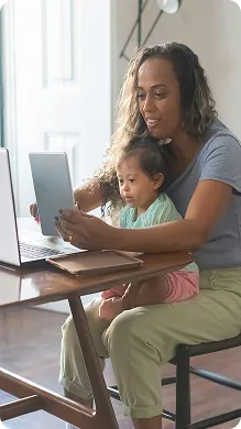 Susan sitting at a table holding a tablet with her toddler on her lap, both looking at the screen.