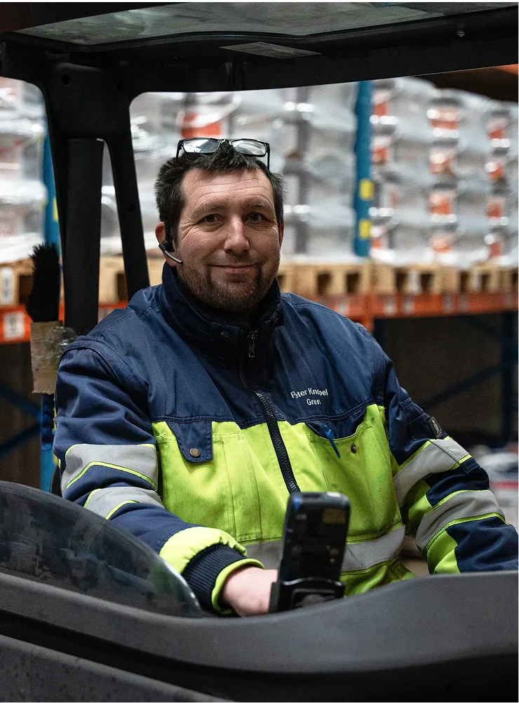 En mand sidder i en gaffeltruck og holder en mobiltelefon.