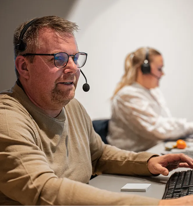 En mand med headset, der bruger en bærbar computer.
